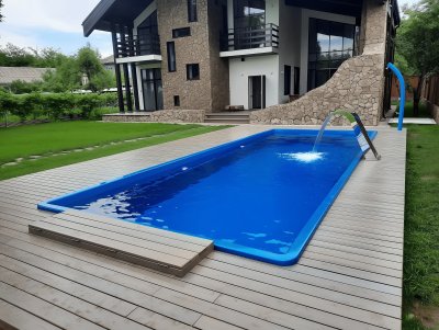 Прямоугольный бассейн с водопадом и террасной доской на заднем дворе дома