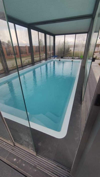 Крытый бассейн с металлическим каркасом и прозрачными стенами внутри павильона